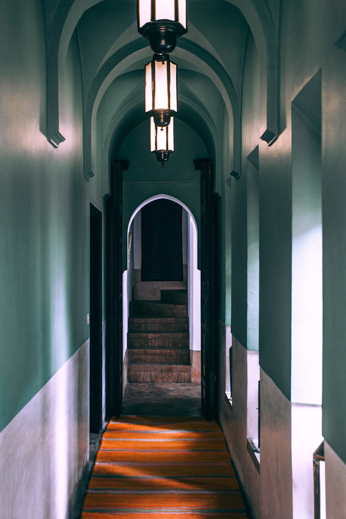 an archway corridor with sky blue wall paint and classic looking pendant lights